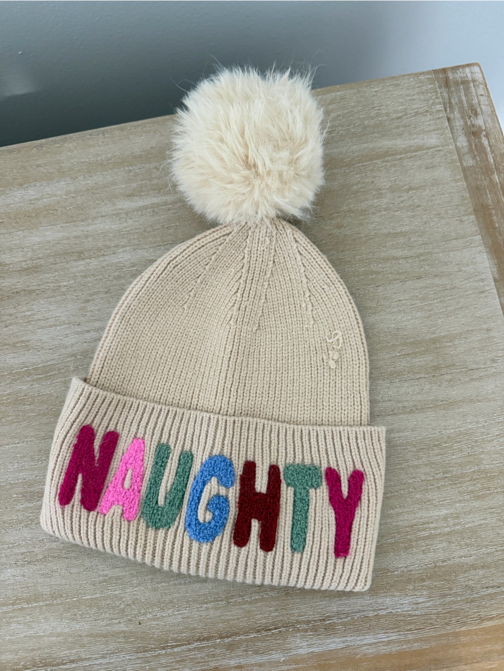 Kids Beige Pom Pom Beanie with Colorful 'NAUGHTY' Lettering